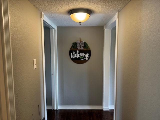 hallway with dark wood-type flooring and a textured ceiling