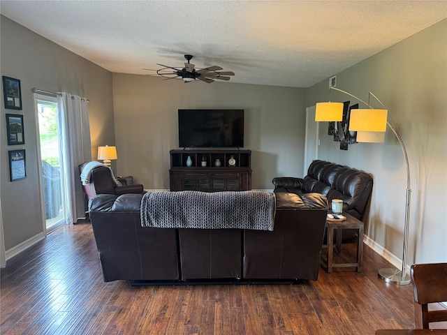 living room featuring dark hardwood / wood-style flooring, ceiling fan, and a textured ceiling