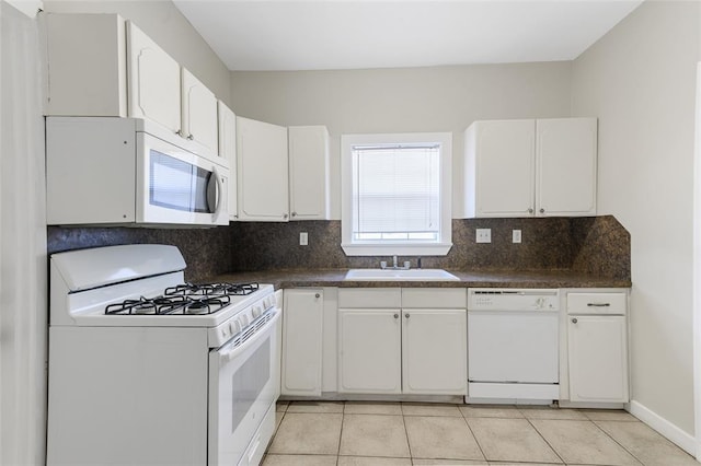 kitchen with dark countertops, white appliances, a sink, and backsplash