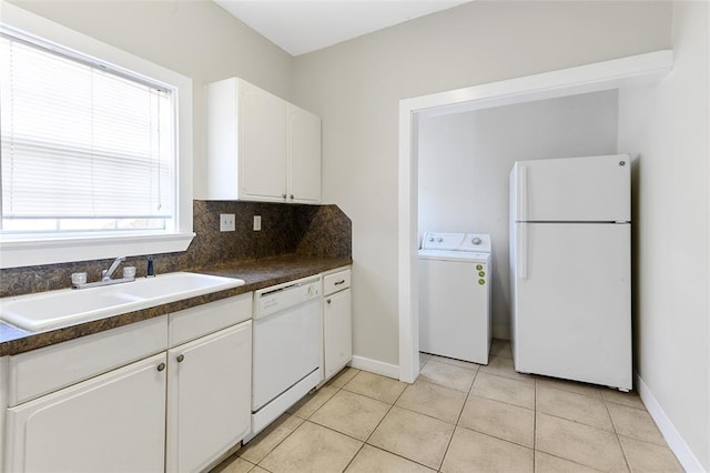 kitchen featuring white appliances, a sink, backsplash, dark countertops, and washer / dryer