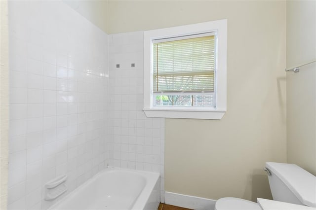 bathroom with baseboards, toilet, and tub / shower combination