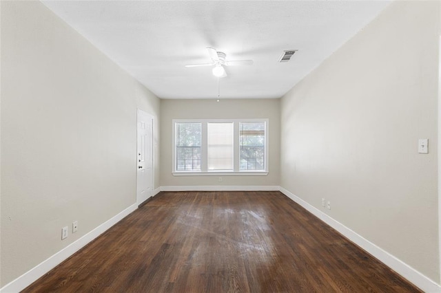 unfurnished room with a ceiling fan, visible vents, dark wood finished floors, and baseboards