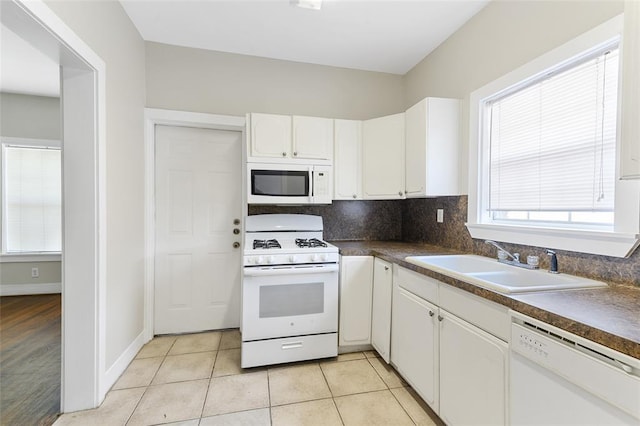 kitchen featuring dark countertops, white appliances, white cabinets, and a sink