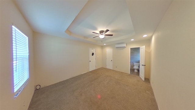 carpeted empty room with ceiling fan, a raised ceiling, and a wall unit AC