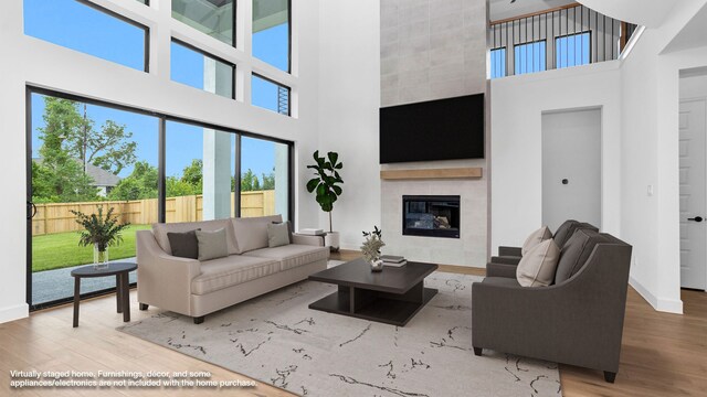 living room featuring a fireplace, hardwood / wood-style floors, and a towering ceiling