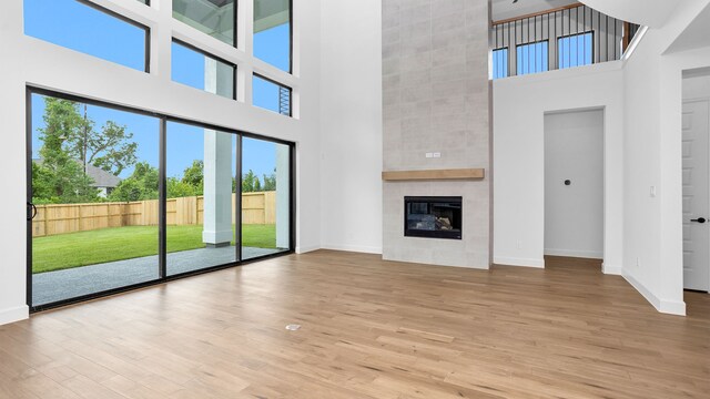 unfurnished living room featuring a high ceiling, hardwood / wood-style floors, and a tile fireplace