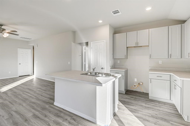 kitchen featuring light hardwood / wood-style floors, a center island with sink, white cabinets, sink, and ceiling fan