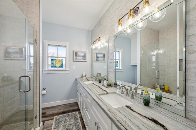 bathroom with double sink, a shower with shower door, wood-type flooring, and large vanity