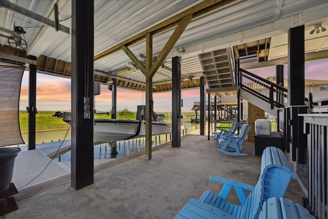 patio terrace at dusk featuring a water view and a dock