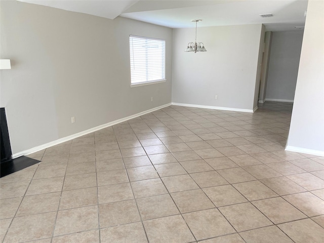 tiled empty room featuring a chandelier