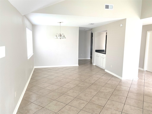 empty room with light tile patterned floors and a chandelier