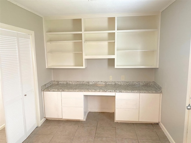 kitchen with light stone countertops, built in desk, crown molding, and light tile patterned floors