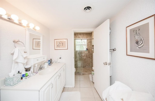 bathroom with tile flooring, vanity, and a shower with shower door