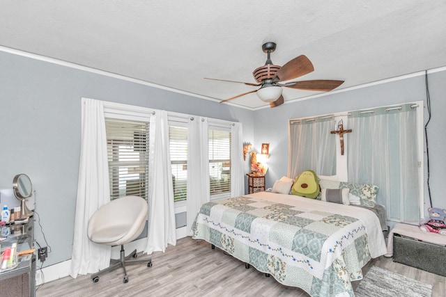 bedroom with light hardwood / wood-style floors, ceiling fan, and a textured ceiling