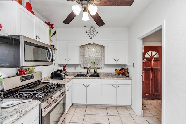 kitchen with appliances with stainless steel finishes, ceiling fan, light tile floors, and white cabinetry