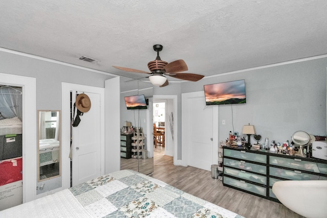 bedroom featuring a closet, a textured ceiling, ceiling fan, and light hardwood / wood-style floors