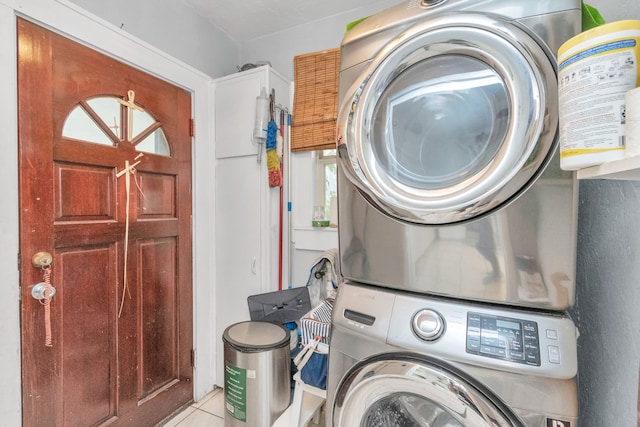 laundry area with stacked washer and dryer and light tile floors