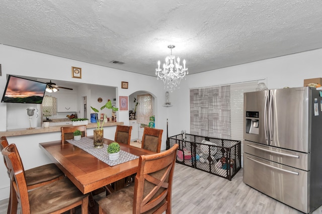 dining area with ceiling fan with notable chandelier, a textured ceiling, and light wood-type flooring