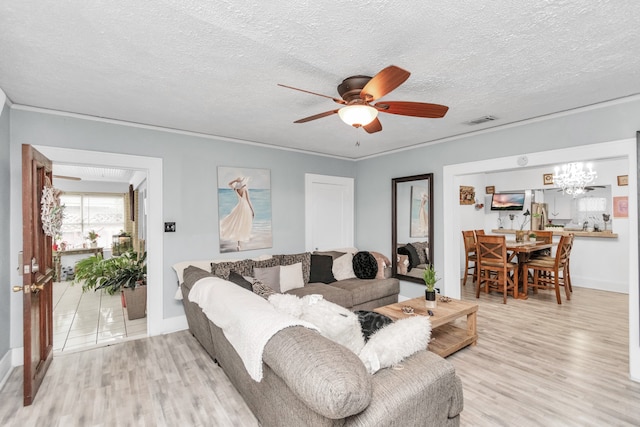 living room featuring ceiling fan with notable chandelier, light tile floors, and a textured ceiling