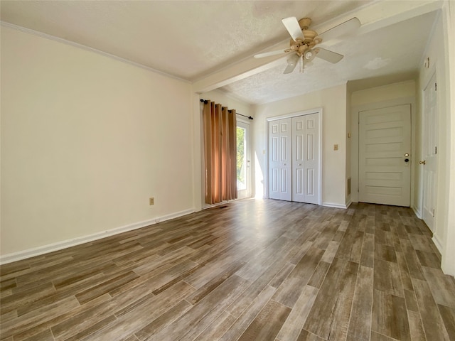 unfurnished bedroom featuring hardwood / wood-style floors, beam ceiling, a textured ceiling, and ceiling fan