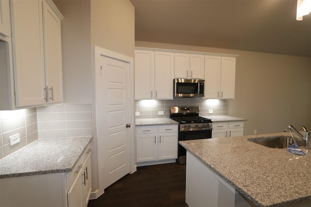 kitchen with stainless steel appliances, sink, white cabinets, and light stone countertops