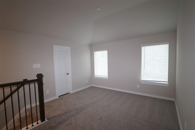 carpeted spare room with vaulted ceiling