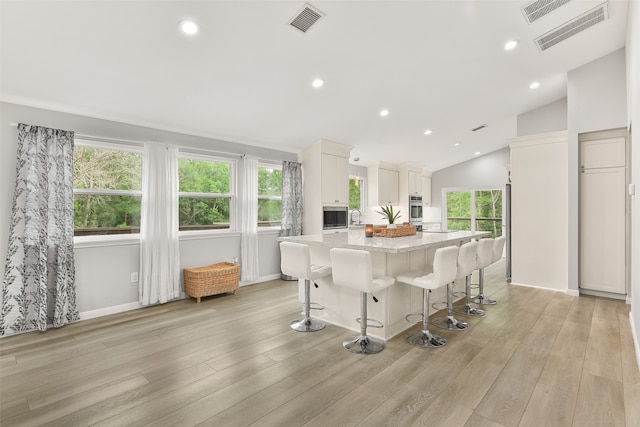 kitchen with a breakfast bar area, a center island, a healthy amount of sunlight, and white cabinetry