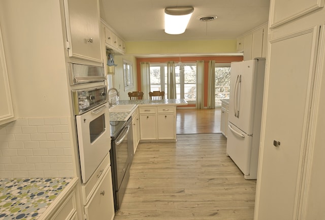 kitchen with white refrigerator, wall oven, sink, light hardwood / wood-style floors, and kitchen peninsula