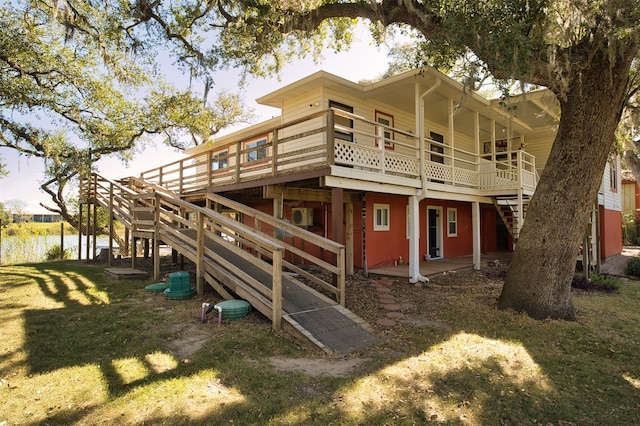 back of property with a yard and a deck with water view