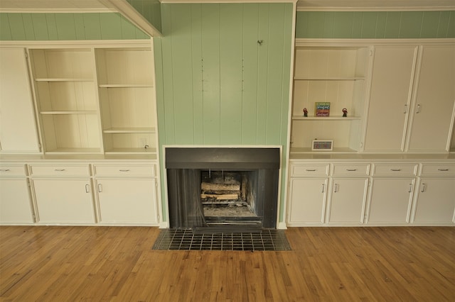 interior space featuring light hardwood / wood-style floors, wood walls, crown molding, and built in features