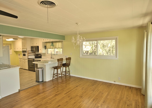 kitchen featuring white cabinets, kitchen peninsula, light hardwood / wood-style flooring, and black appliances