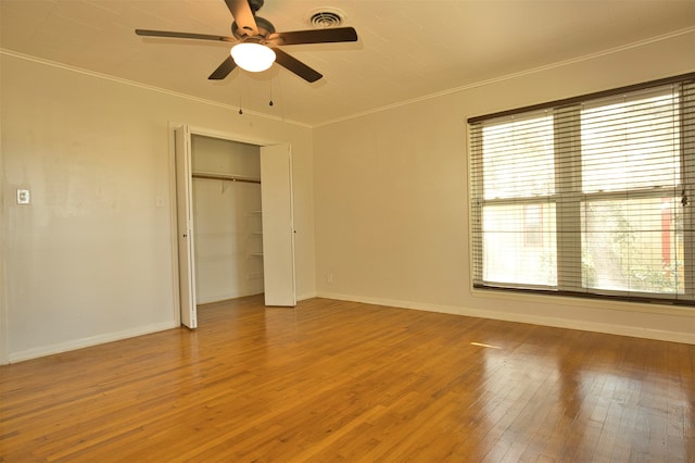 unfurnished bedroom featuring crown molding, wood-type flooring, multiple windows, and ceiling fan