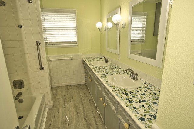 bathroom featuring tiled shower / bath, vanity, wood-type flooring, and tile walls