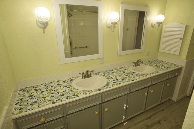 bathroom with hardwood / wood-style flooring, vanity, and a tile shower