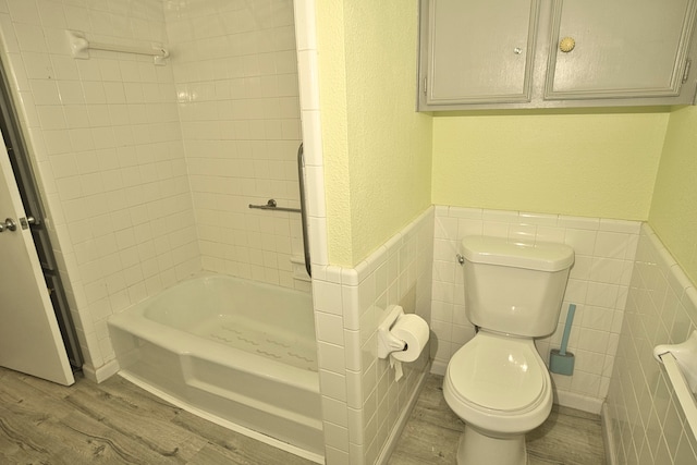 bathroom featuring tile walls, wood-type flooring, toilet, and tiled shower / bath