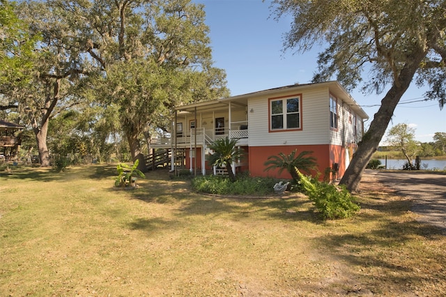 raised beach house with a porch, a water view, and a front lawn