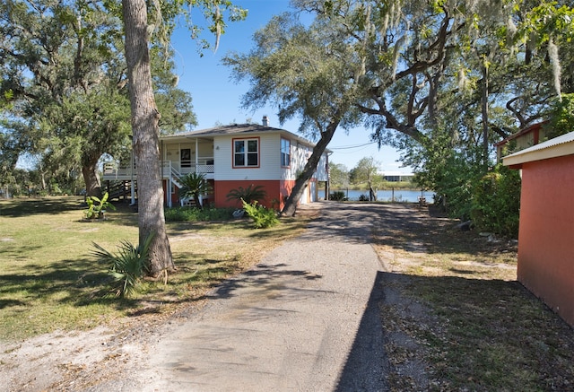 view of side of property featuring a yard, a water view, and a porch