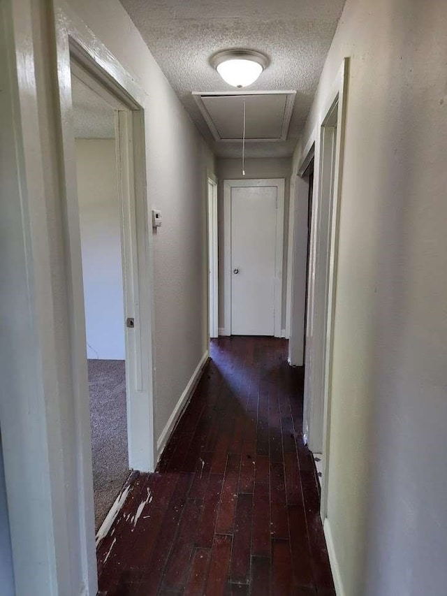 corridor with a textured ceiling and dark carpet