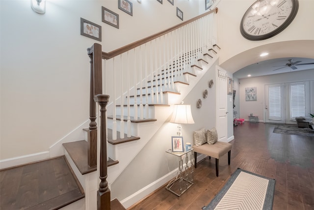 stairway with a towering ceiling, hardwood / wood-style floors, and ceiling fan