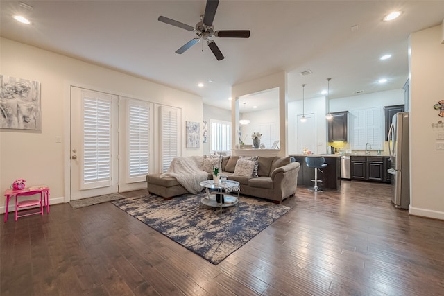 living room featuring sink, dark wood-type flooring, and ceiling fan