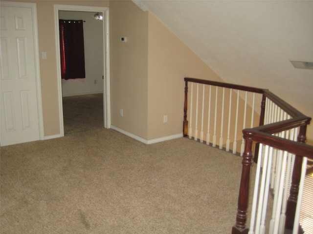 unfurnished bedroom featuring light colored carpet, lofted ceiling, and a nursery area