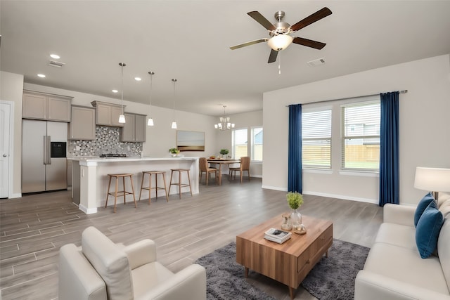 living room with ceiling fan with notable chandelier