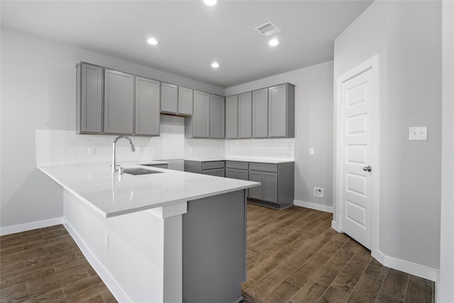 kitchen with dark hardwood / wood-style floors, gray cabinetry, sink, and kitchen peninsula