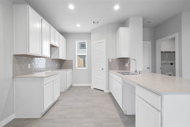 kitchen with white cabinets, sink, light wood-type flooring, and decorative backsplash