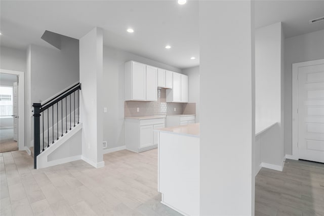 kitchen featuring white cabinets, light hardwood / wood-style floors, and decorative backsplash