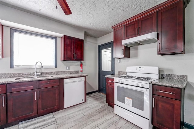 kitchen featuring white appliances, sink, light stone counters, ceiling fan, and a textured ceiling