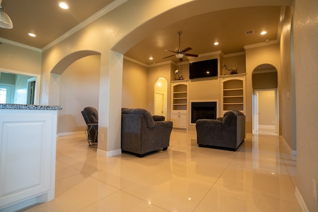 living room with built in features, crown molding, ceiling fan, and light tile flooring