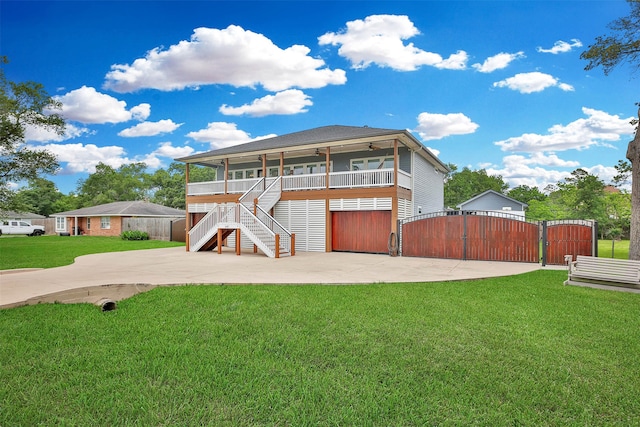 rear view of house featuring a garage, covered porch, and a lawn