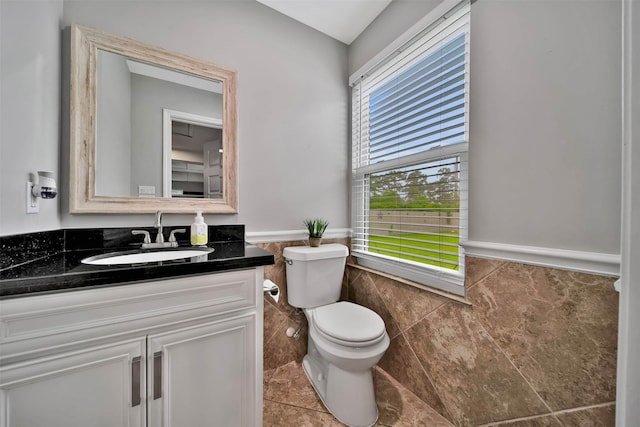 bathroom featuring vanity, toilet, tile floors, and tile walls