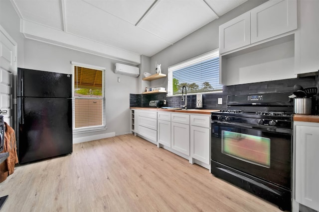 kitchen featuring tasteful backsplash, an AC wall unit, light wood-type flooring, and black appliances